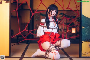 A woman in a red and white outfit is tied up.