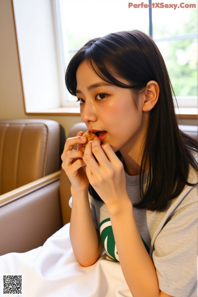 A woman sitting on a couch eating a donut.