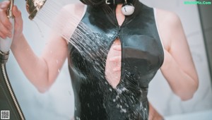 A woman in a black cat suit is taking a shower.