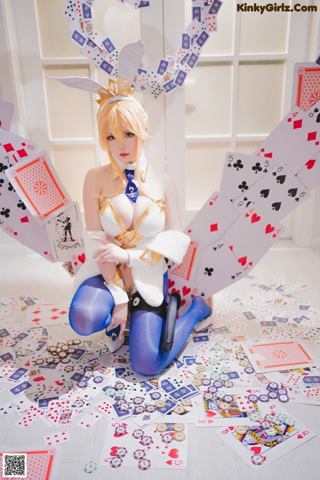 A woman sitting on the floor surrounded by playing cards.