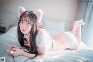 A woman in a pink lingerie sitting on a bed.