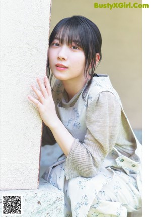 A young woman sitting on a wooden bench.