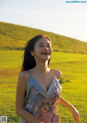 A woman in a pink bra top and blue jeans laughing.