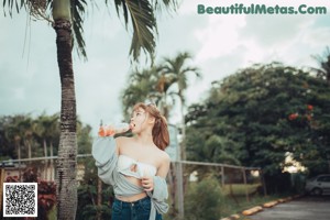 A woman in a bikini standing next to a palm tree.