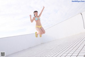 A woman in a pink bikini sitting on a ledge.