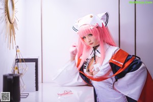 A woman with pink hair sitting on a white couch.