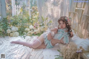 A woman in a blue and white outfit sitting on a bed.