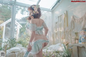 A woman in lingerie sitting on a bed surrounded by flowers.