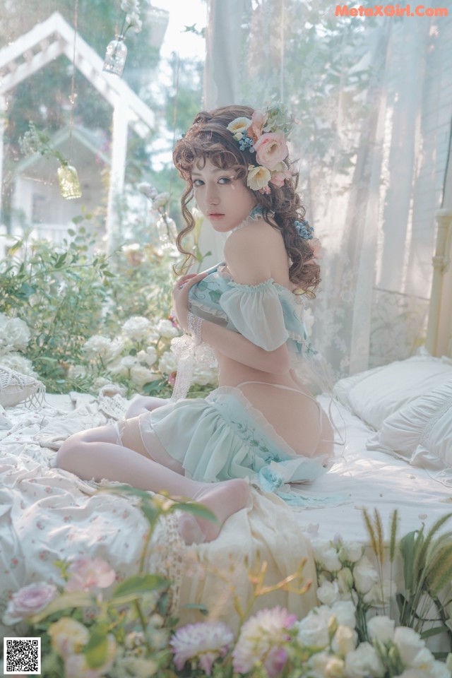 A woman sitting on a bed surrounded by flowers.