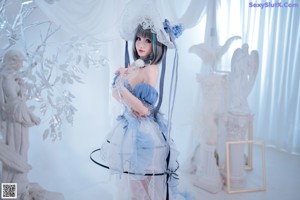 A woman in a blue and white dress sitting on a chair.
