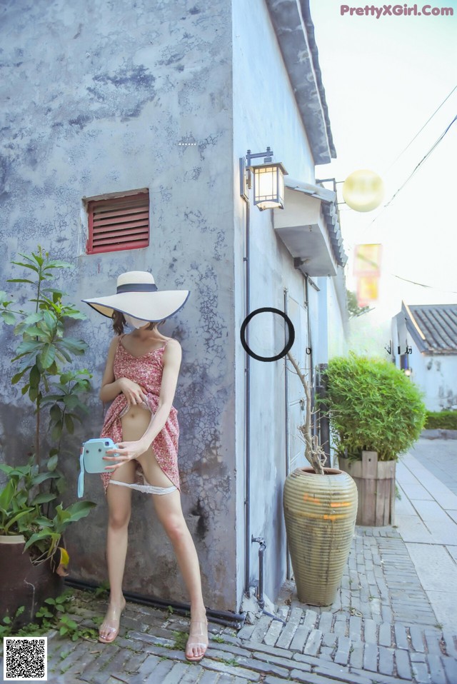 A woman in a pink dress and a white hat is posing for a picture.