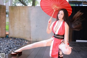 A woman in a red and white outfit holding an umbrella.