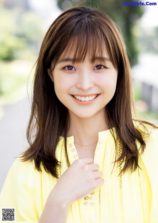 A young woman in a yellow shirt smiles at the camera.