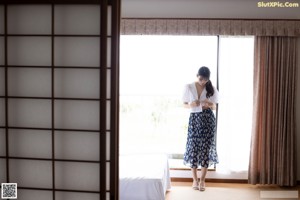 A woman in a white bra and blue skirt laying on a bed.