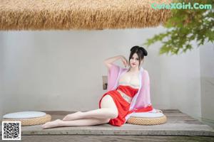 A woman in a red dress sitting on a table.