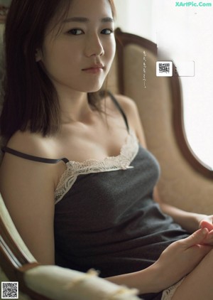A woman in a white bra sitting on a bed.