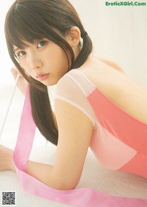 A woman in a pink leotard holding a pink ribbon.