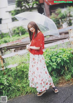 A woman in an orange kimono holding an umbrella.