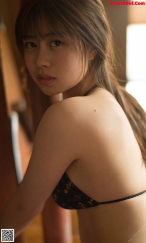 A woman in a black bikini sitting on a window sill.