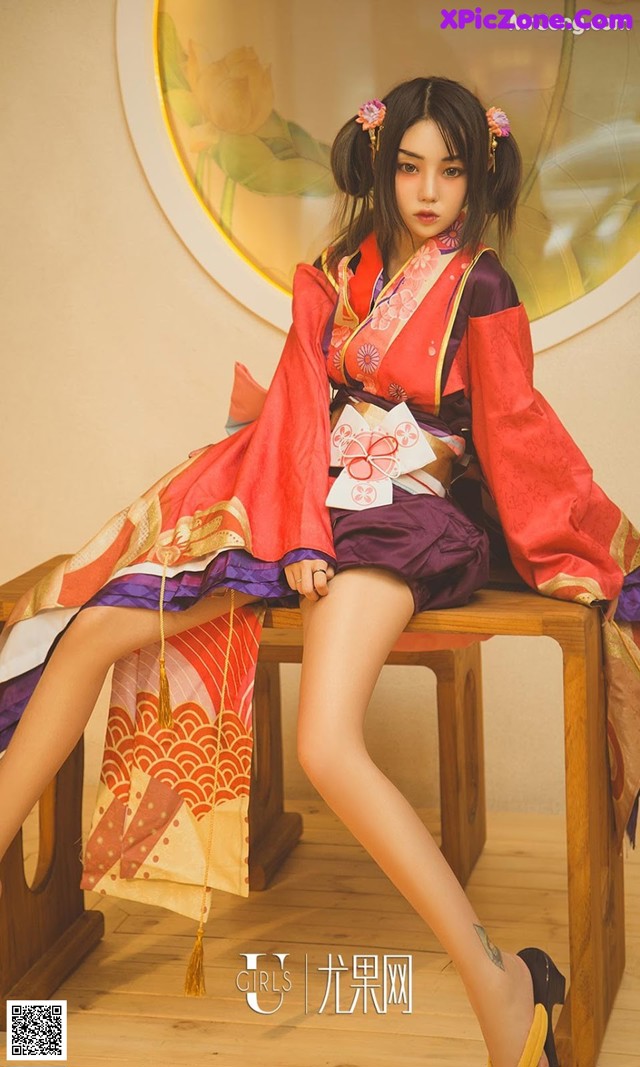 A woman in a kimono sitting on a wooden bench.