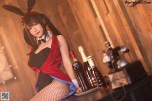 A woman in a bunny costume sitting at a table with a bottle of wine.