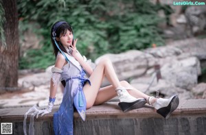 A woman in a blue and white outfit sitting on a rock.