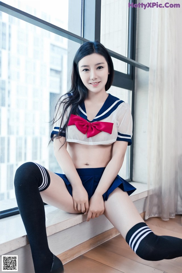 A woman in a sailor outfit sitting on a window sill.