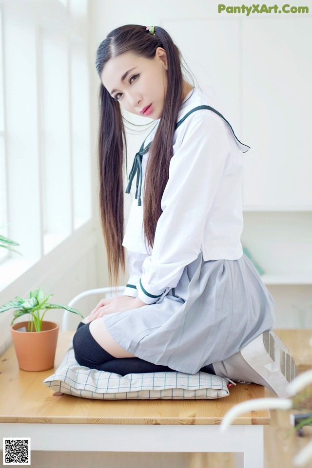 A woman in a school uniform sitting on a table.
