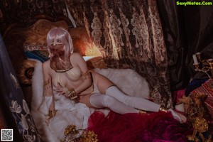 A woman in a white outfit sitting on a bed.