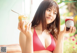 A woman in a blue and white bikini standing in a bathtub.