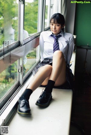 A woman in a school uniform sitting on a window sill.