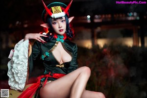 A woman dressed as a demon sitting on the ground.