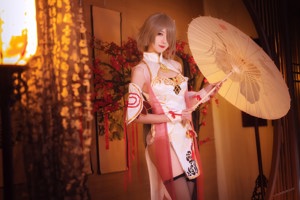 A woman sitting on a bed holding a fan.