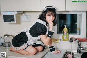 A woman in a maid outfit cleaning a kitchen counter.