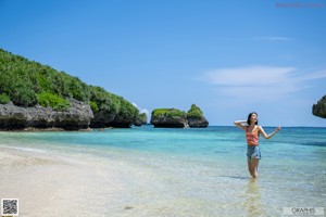 A woman in a towel on the beach posing for the camera.