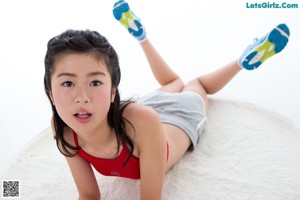 A woman in a red tank top laying on a white rug.