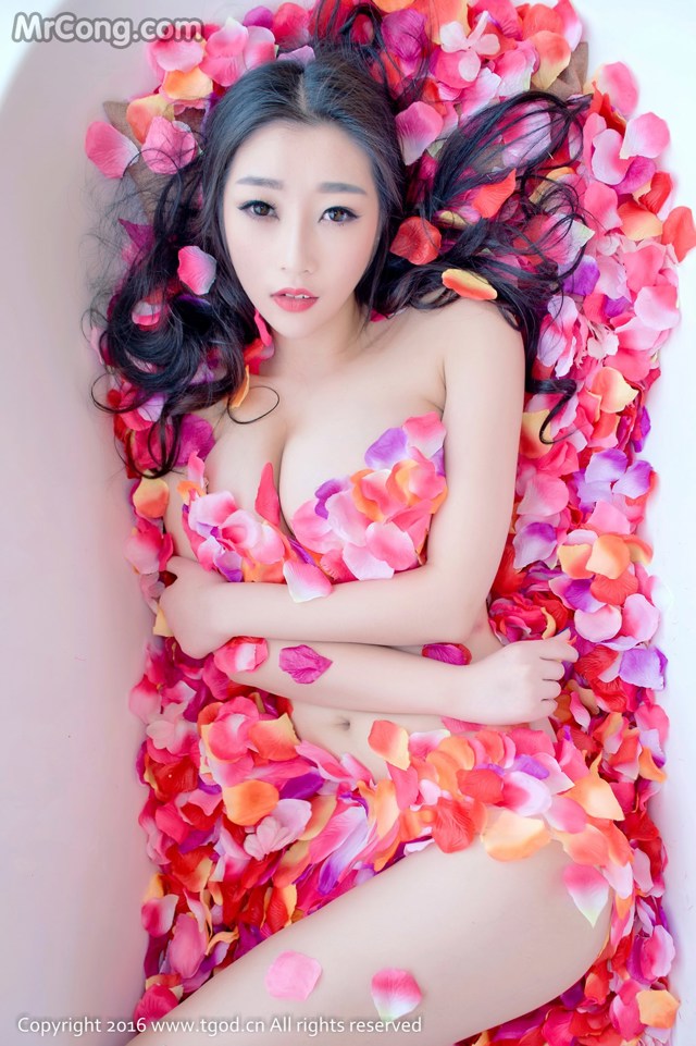 A woman laying in a bathtub covered in rose petals.