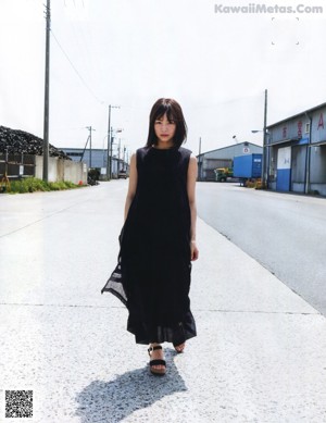 A woman leaning against a brick wall with her hand on her chin.