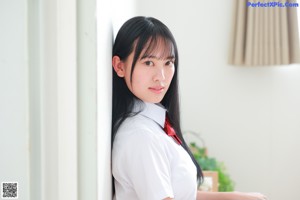 A woman in a school uniform standing on a bed.