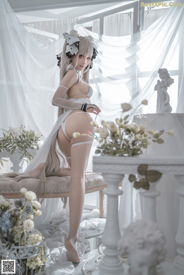 A woman in a white lingerie sitting on a chair.