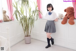 A woman in a school uniform sitting on a bed.