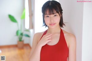 A woman in a red bathing suit sitting on the floor.