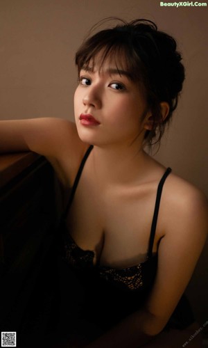 A woman in a black tank top looking out a window.